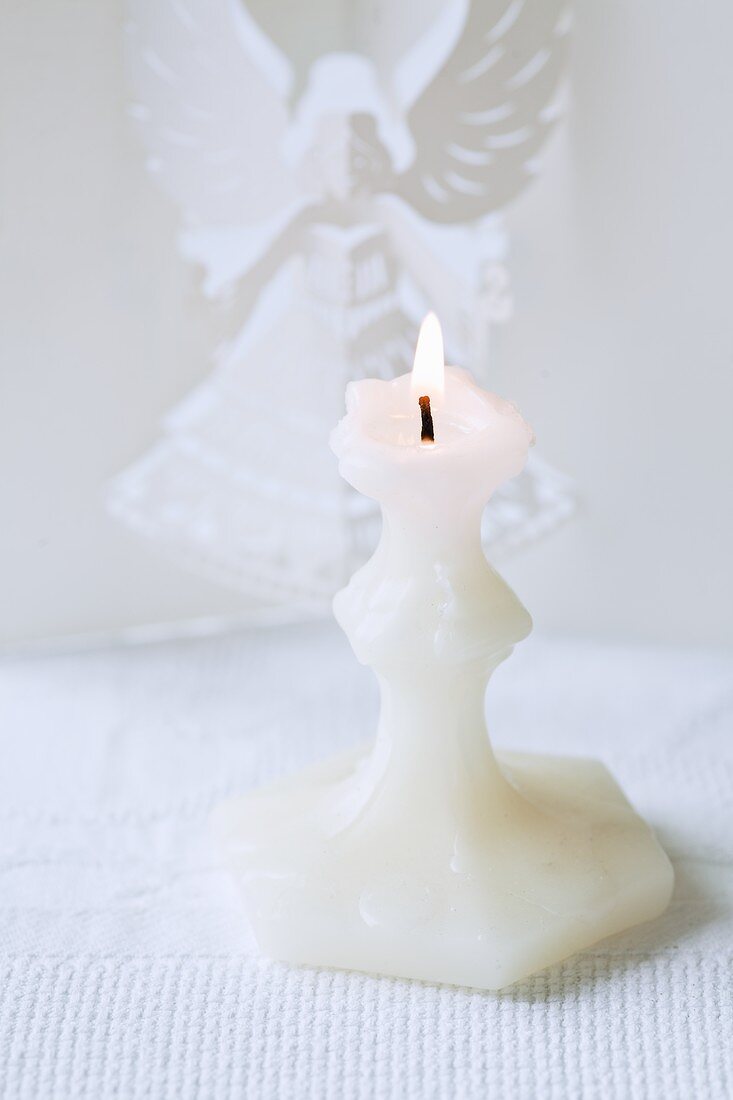 weiße Kerze, dahinter Engel aus Papier gefaltet