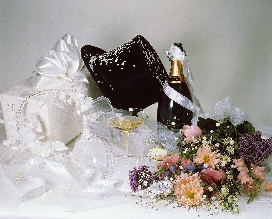 Hochzeitsgeschenke, Zylinder, Blumen und Sekt auf einem Tisch