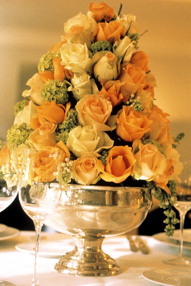 Elegantes Rosenarrangement in Silbervase auf einem Tisch