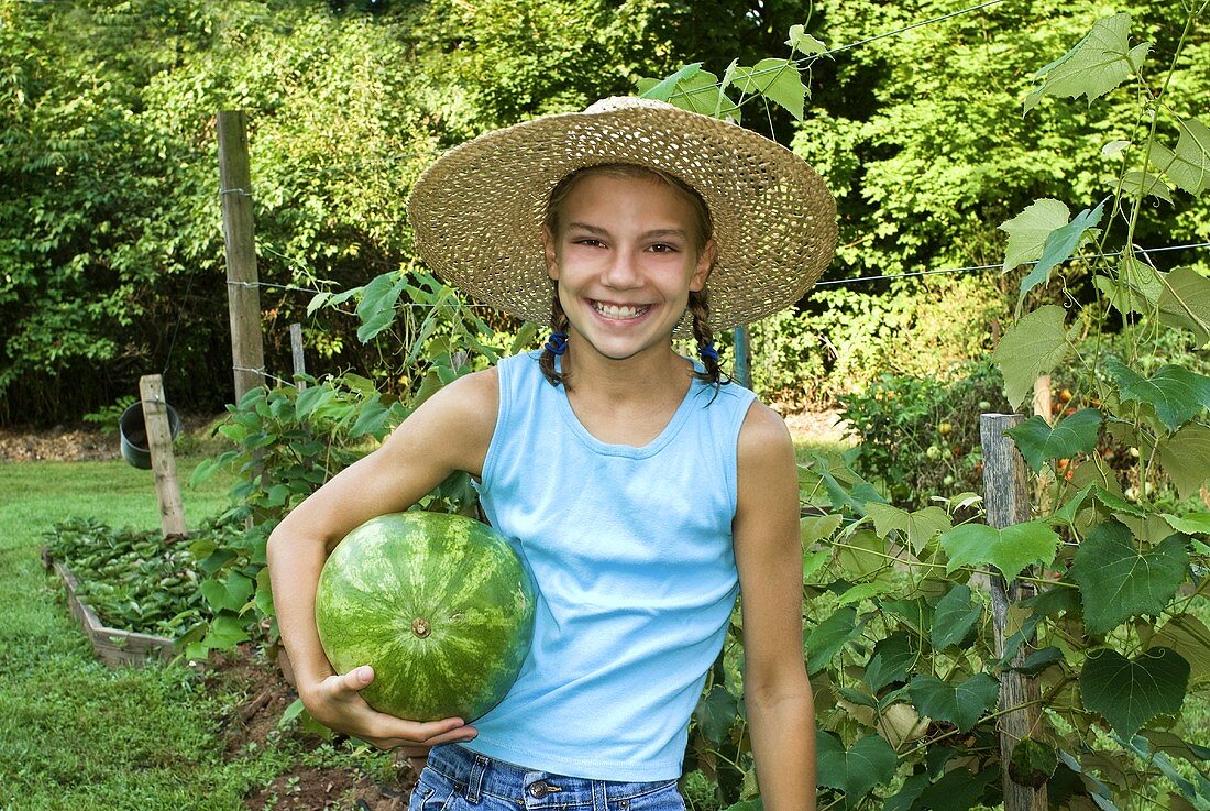 Mädchen hält eine Wassermelone im Garten