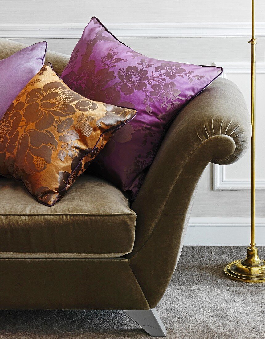 Cushions made of a shiny orange and purple material on a sofa