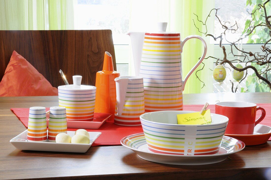 Colourful, striped breakfast crockery and coffee pot and Easter decoration