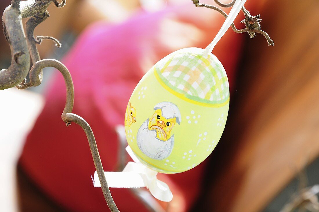 A painted Easter egg hanging on a twig