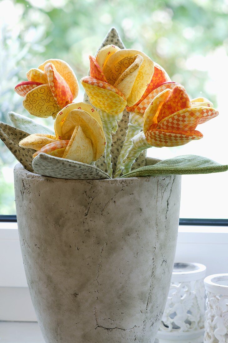 A grey stone pot decorated with fabric flowers