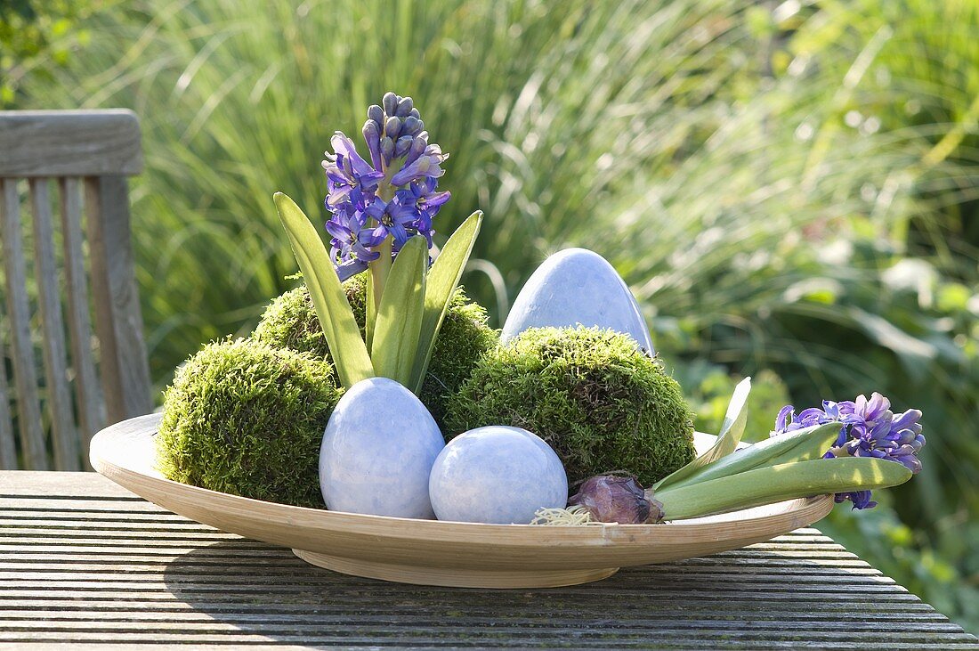 An Easter nest on a garden table with flowers and moss