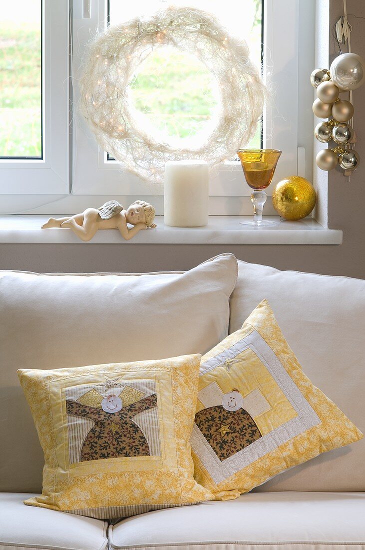 Sofa cushions with an angel motif under a festively decorated window