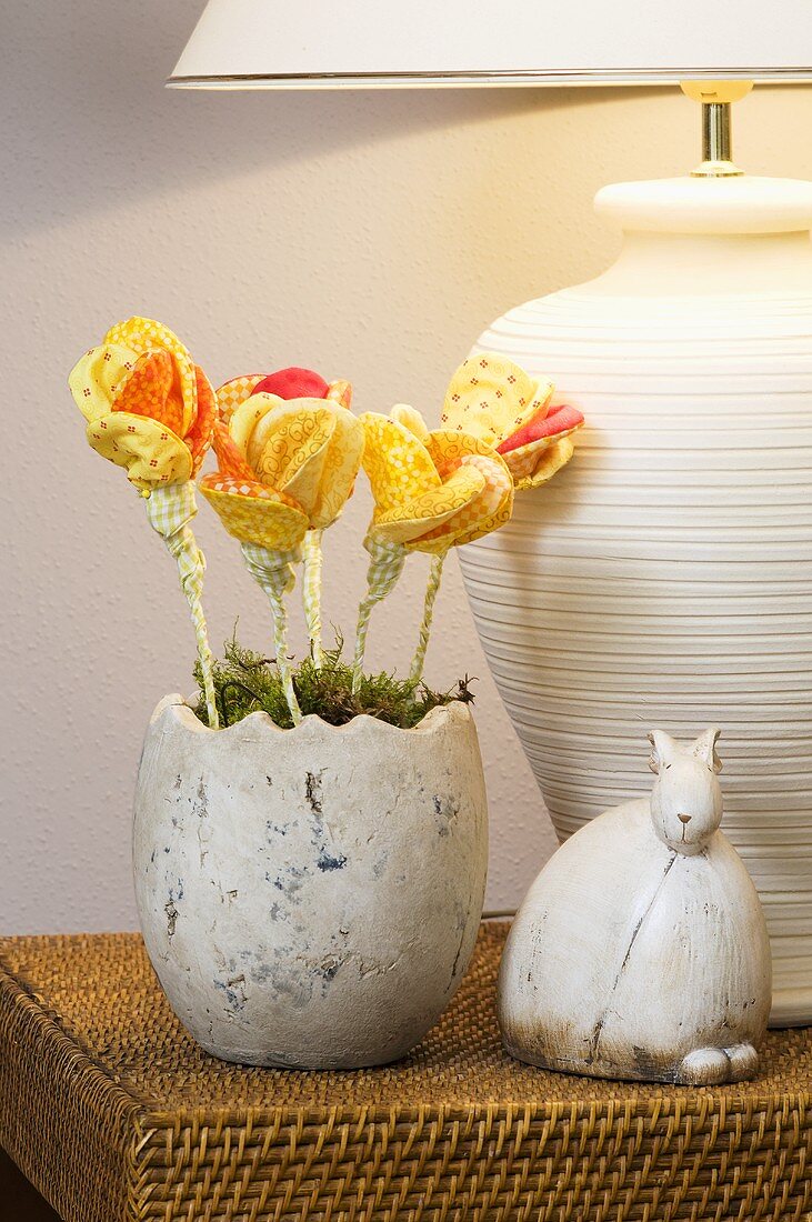 Dekoriertes Osternest mit gelben Dekoblumen und einem Keramikhasen