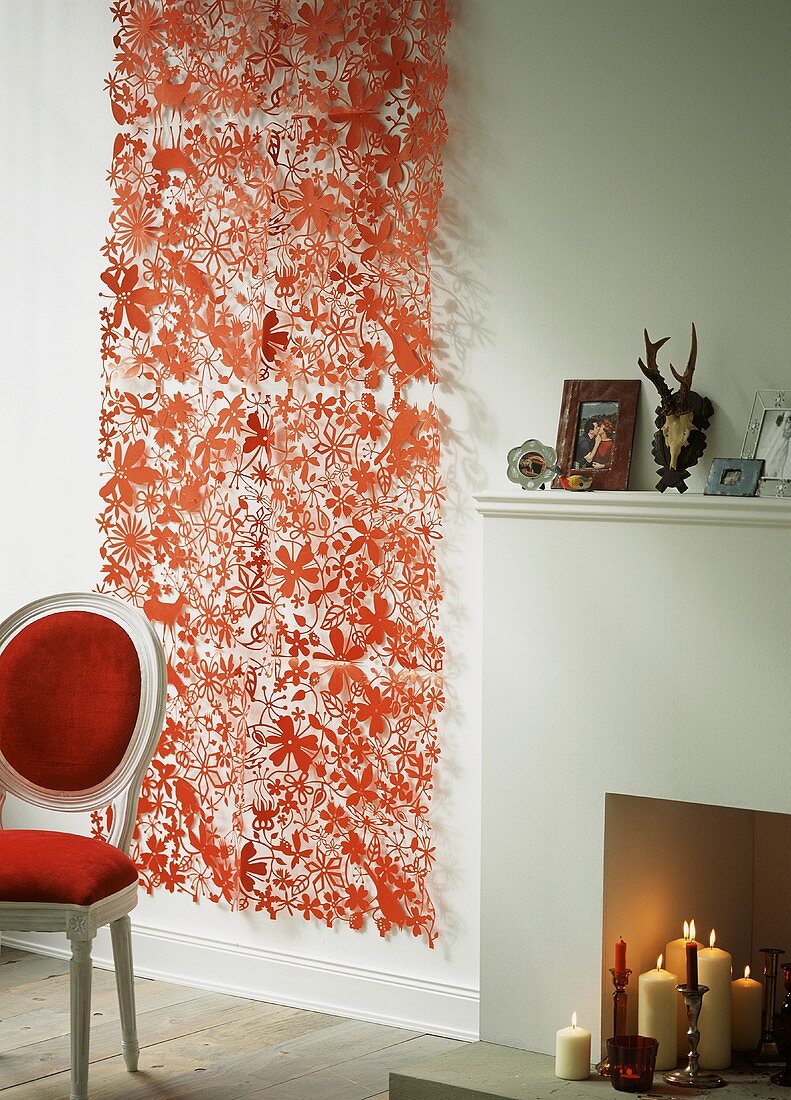 A decorative piece of red paper hanging on the wall next to a fireplace