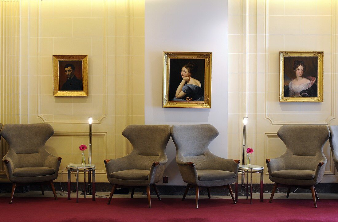 Grey winged armchairs in a spacious hotel hallway a with illuminated floor lamps