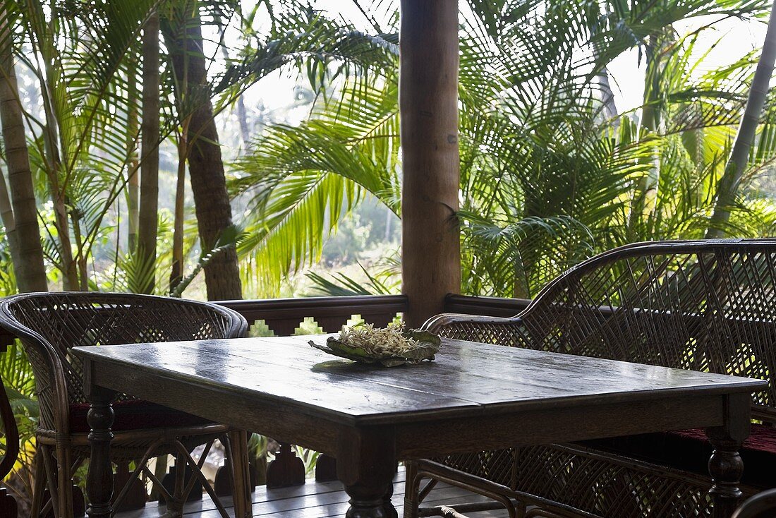 Wicker furniture in the corner of a terrace in tropical surroundings