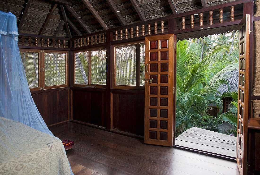 A bedroom in an Asian-style hut with a view of palm trees