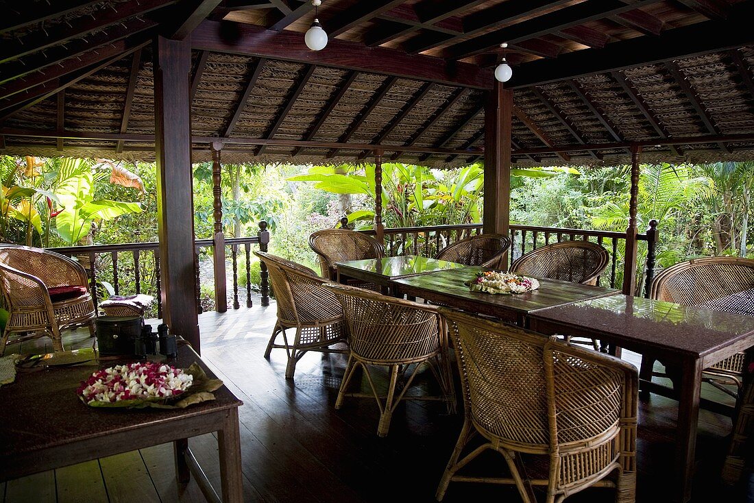 A covered terrace with wicker furniture and ball lights in a tropical surroundings