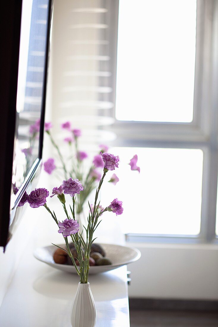 Zarter Blumenstrauss mit violetten Blüten auf einer weissen Ablage
