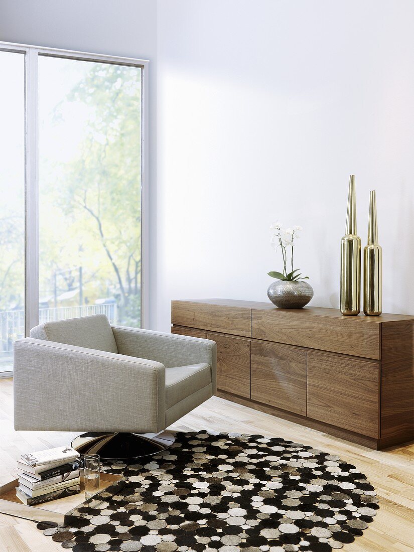Wohnraum im Designerstil mit Drehsessel, rundem Teppich und Sideboard aus Holz
