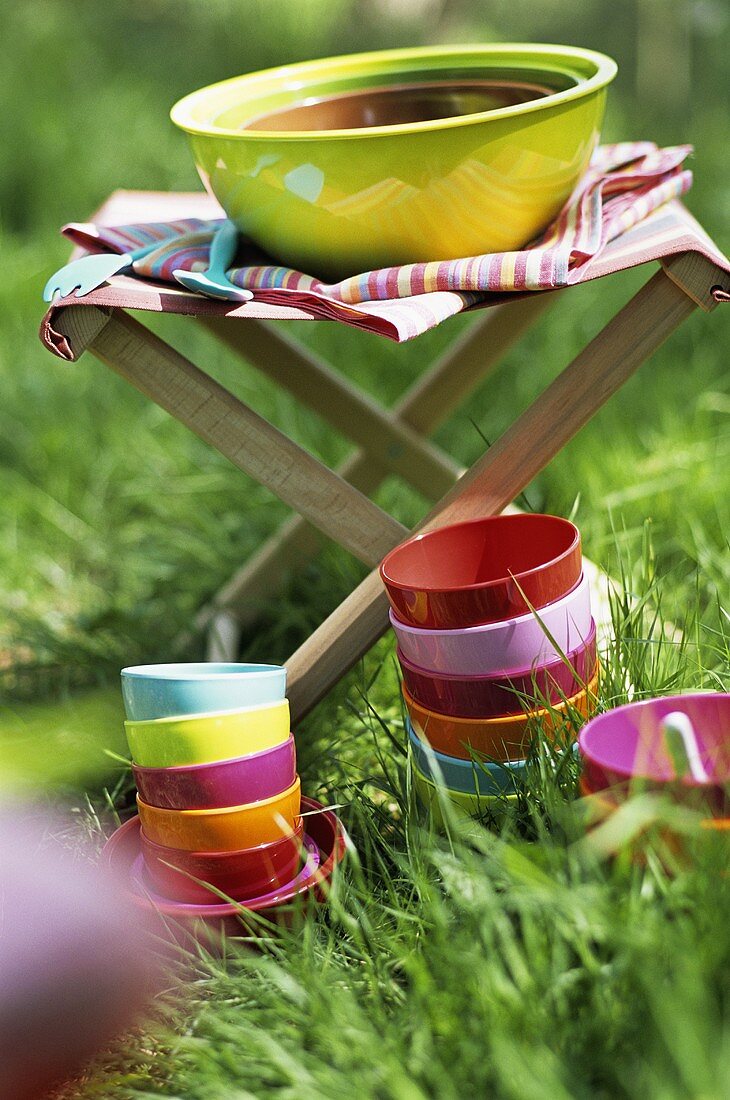 Colourful bowls in the grass and a large bowl on a folding stool