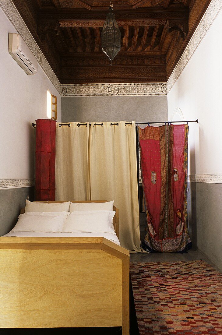 Marokkanisches Schlafzimmer mit Bett, Holzdecke & Vorhängen als Raumteiler