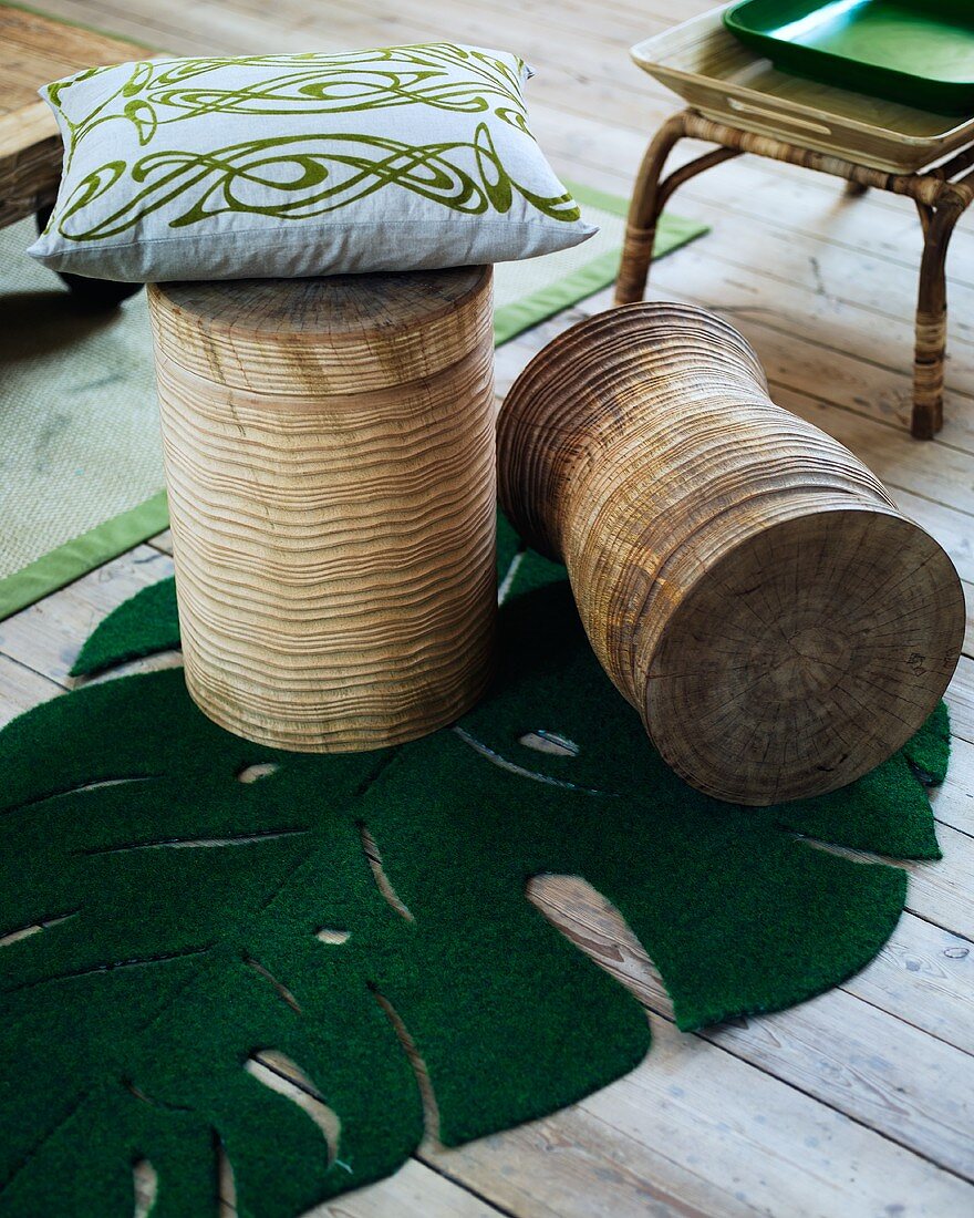 Holzhocker mit Kissen und Teppichmatte in Form eines Blattes