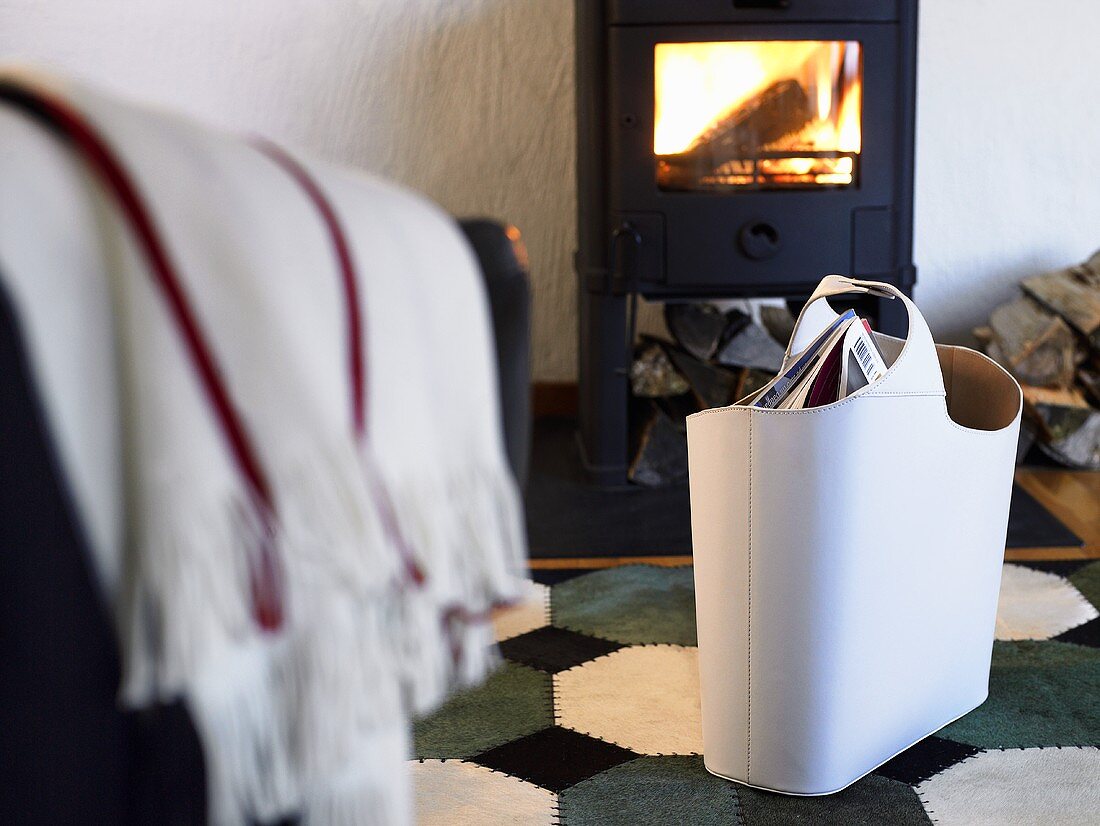 White leather bag in front of a wood burning stove with fire