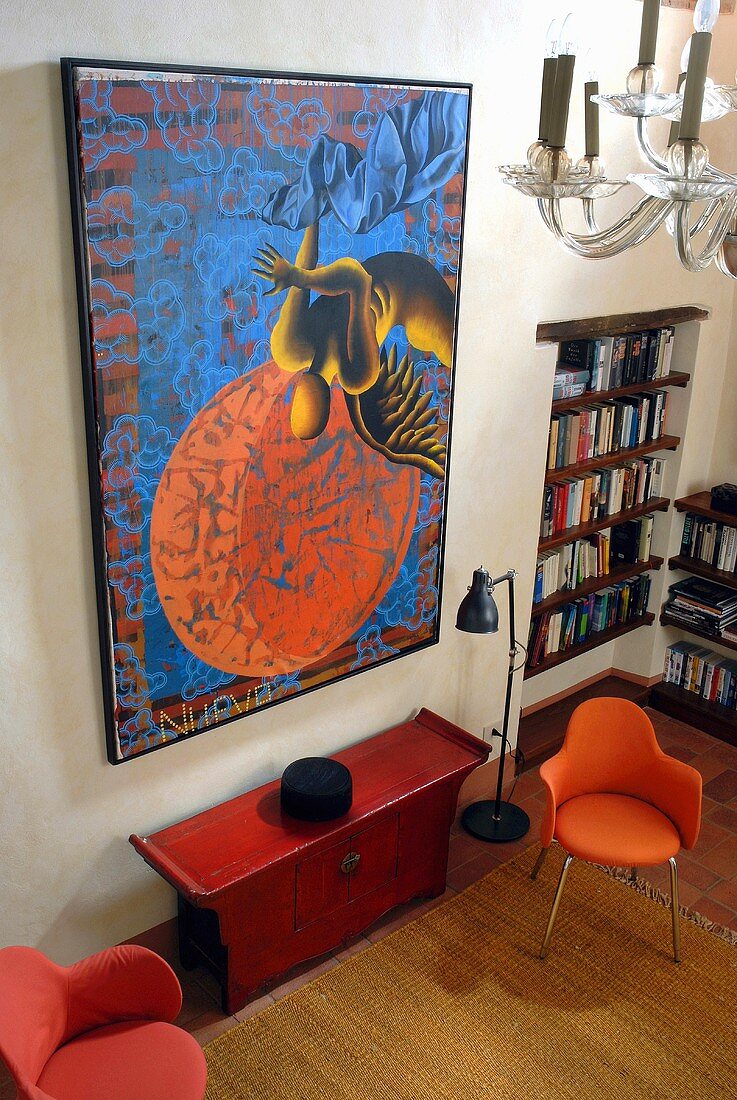 View of a red lounge chairs and side board under a picture in a living room