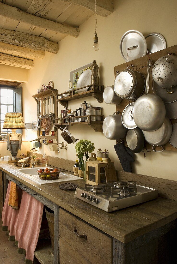 Küchenzeile mit rustikaler Holzarbeitsplatte und Kochgeschirr an Holzboard gehängt