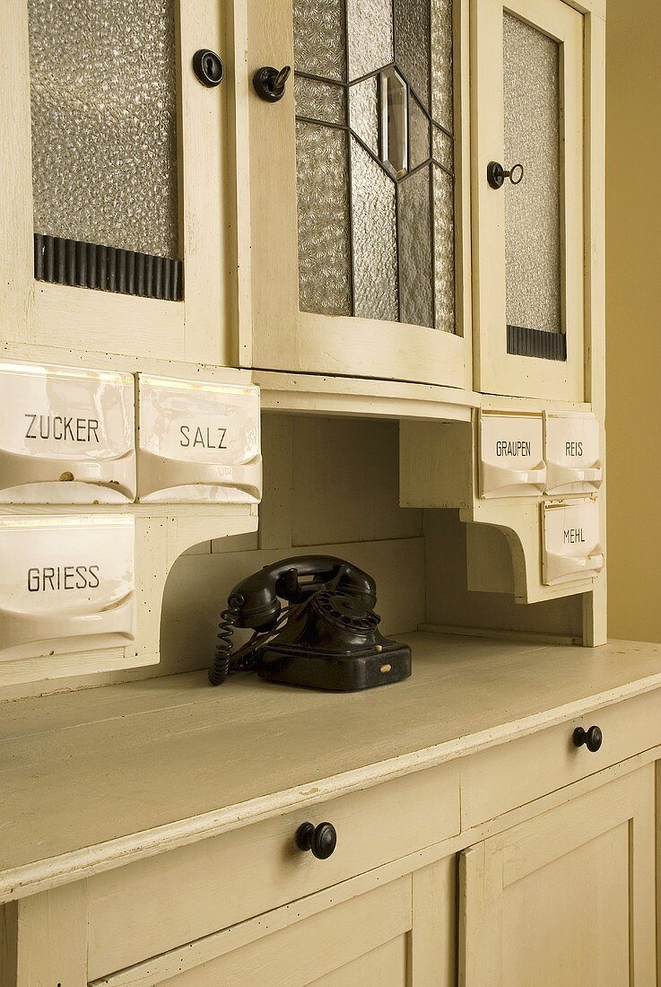 Weisser Geschirrschrank mit Vorratsbehältern aus Porzellan und Vintage Telefon