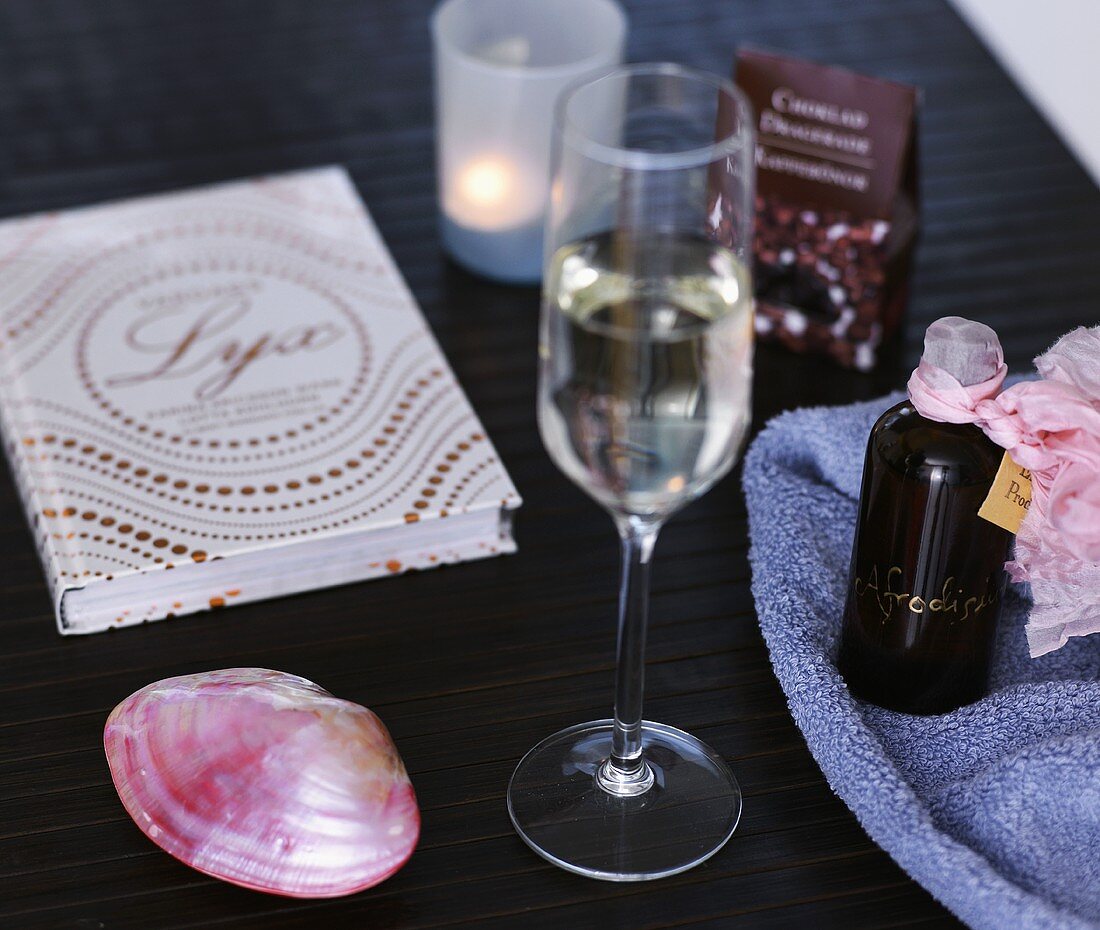 Stemware glass next to a rose colored shell with items for the bathroom on a black counter