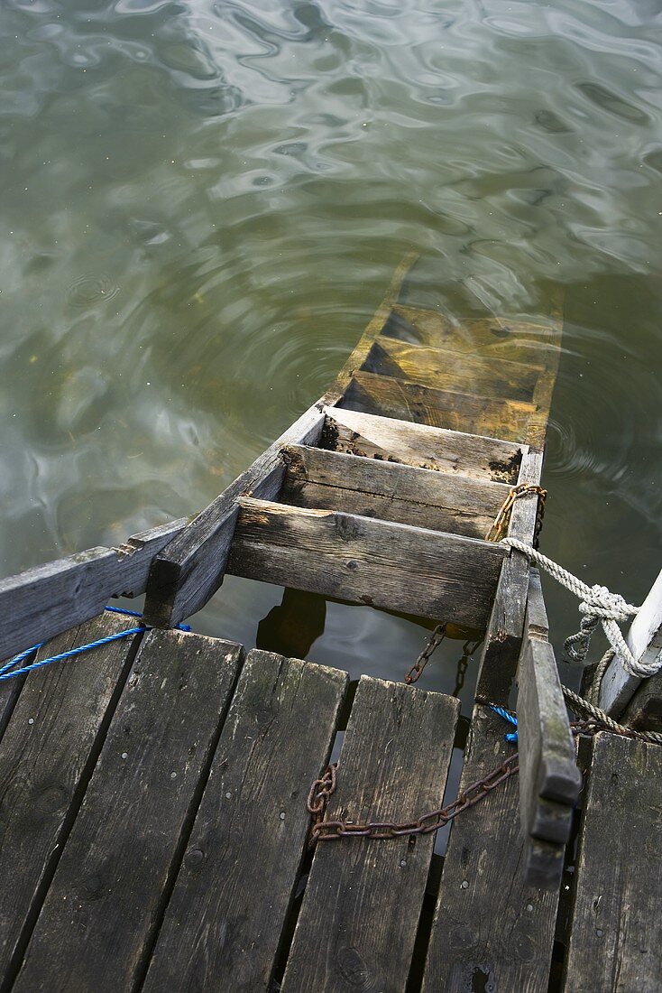 Wooden ladder in water, tied to a jetty