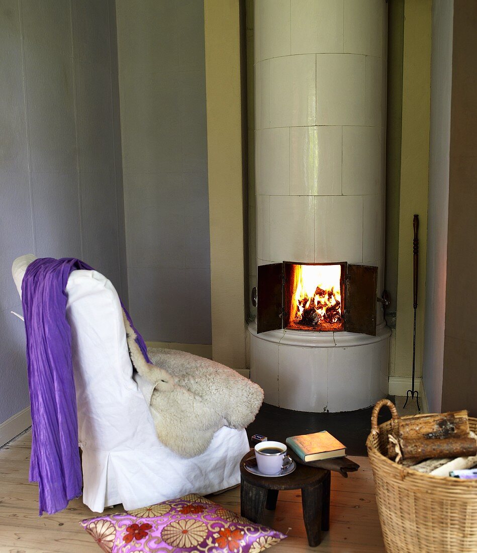 A cosy coffee break in front of a wood burning stove with white tiles and an open door with a view of the crackling fire