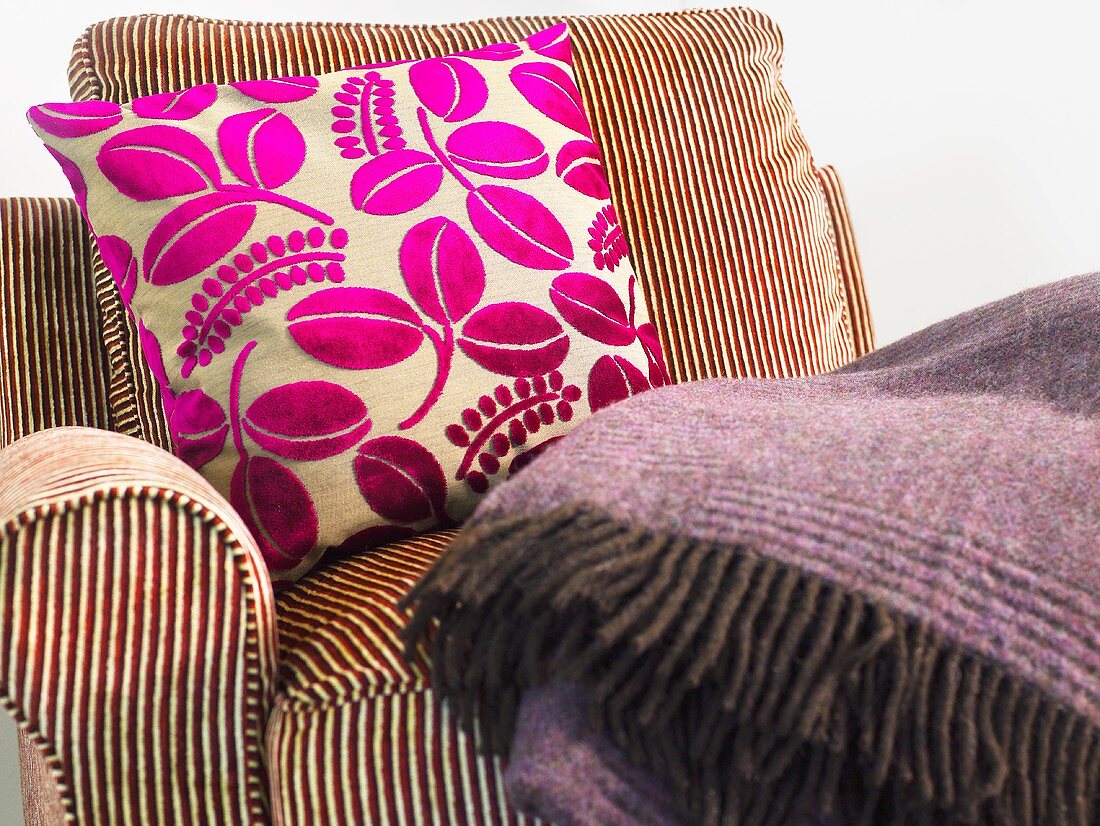 Pillows with pink floral fabric on a striped upholstered chair
