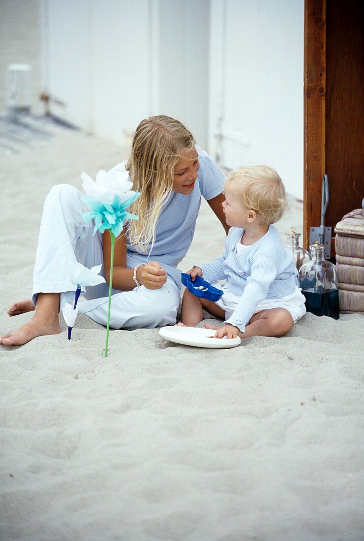 Mädchen spielt mit kleinem Kind im Sand