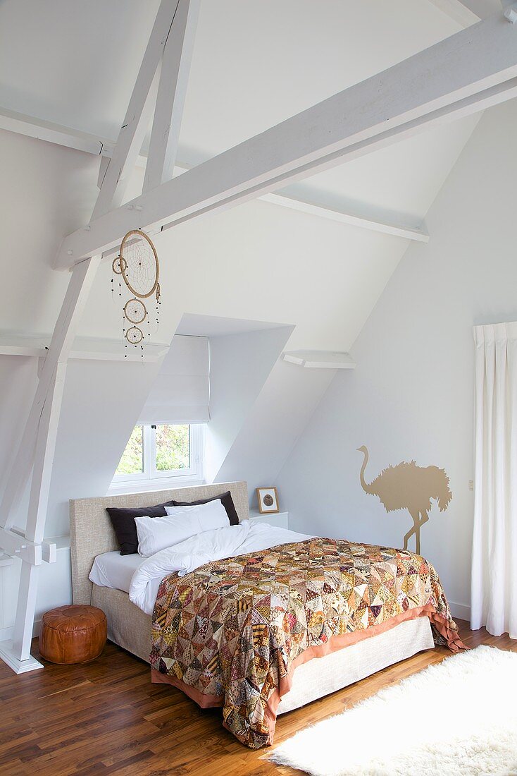 A white-painted attic with a double bed under the window