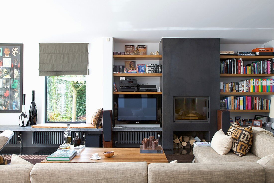 A living room with a black, built-in fireplace between built-in shelves with a view through a window with a shelf underneath