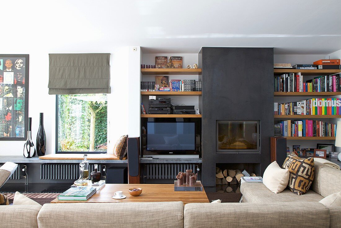 Wohnraum mit eingebautem Kamin schwarz gestrichen zwischen Einbauregal, Blick zum Fenster mit Ablage