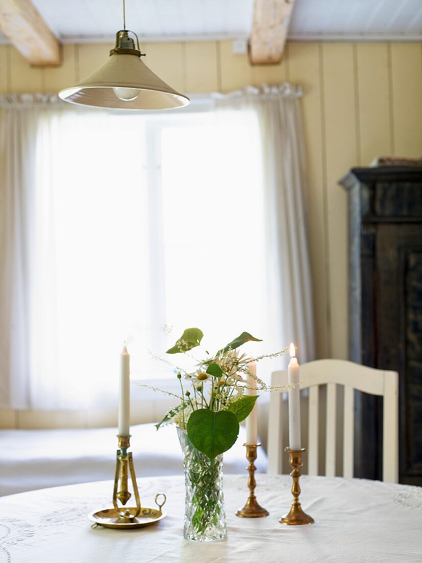 Kerzenlicht und Blumenvase auf weißem Tisch mit Blick auf Fenster