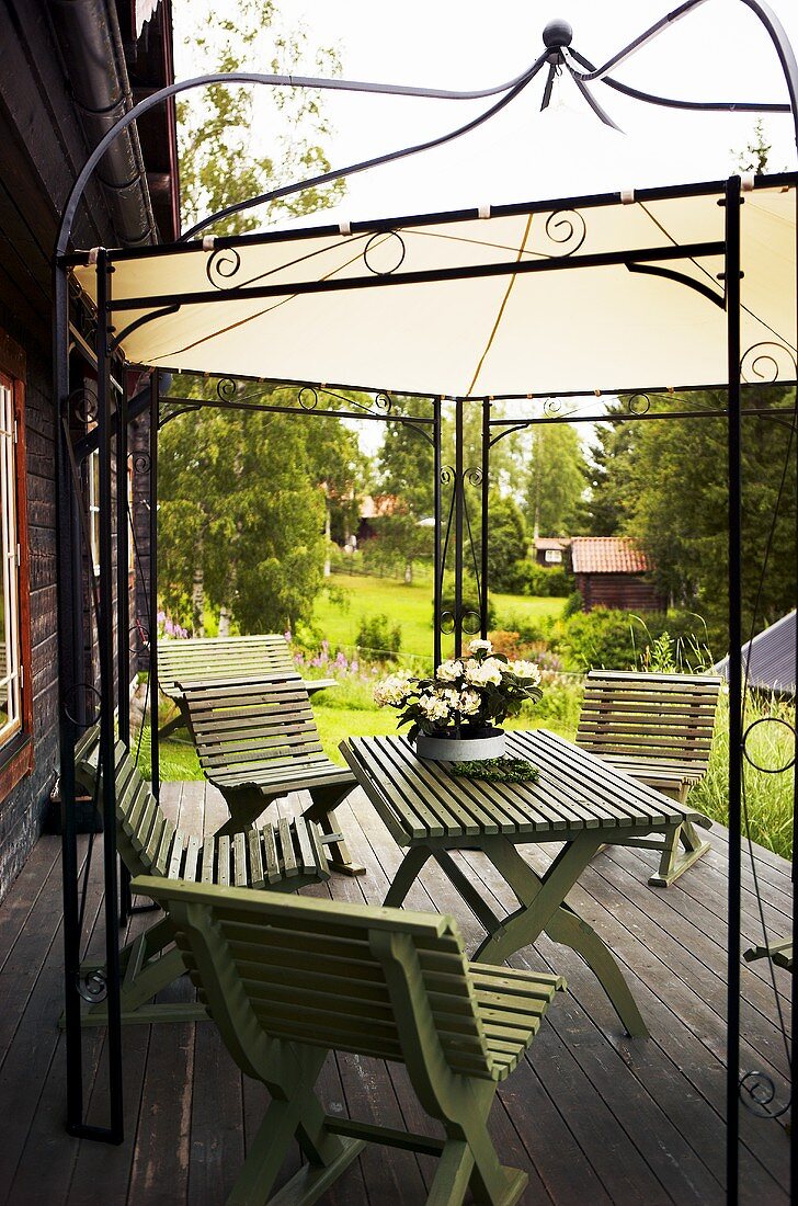 Garden furniture on a wooden terrace under a canopy with a metal frame