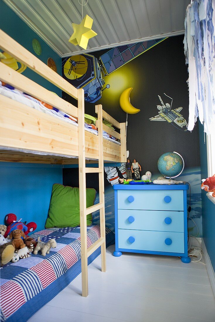 A child's bedroom with a bunk bed and a blue chest of drawers in front of a dark blue wall