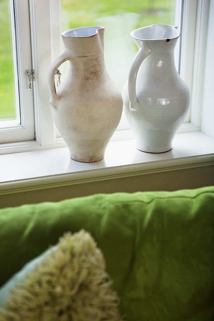 weiße Keramikkrüge auf der Fensterbank