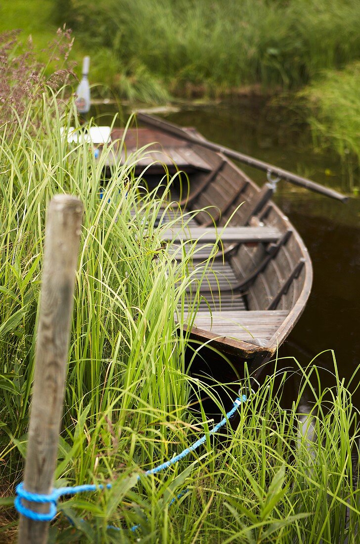Festgemachtes Holzboot am Flussufer