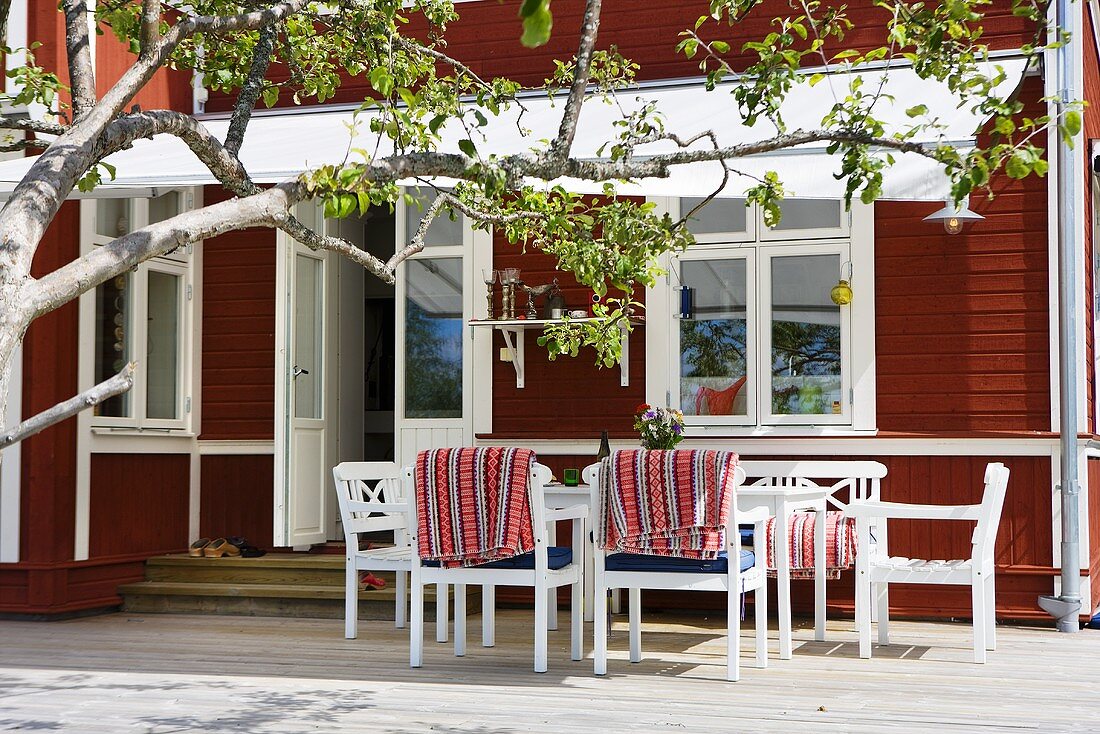 White patio furniture under a marquee in front of a red brown wooden facade