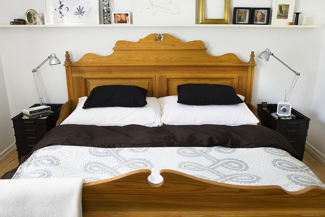 A country-style wooden bed with black cushions
