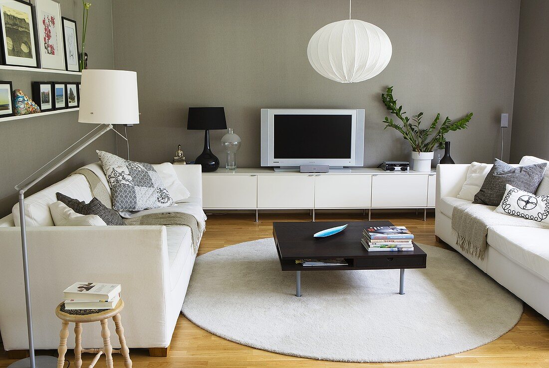 A living room with a white sofa and a black coffee table against a grey wall