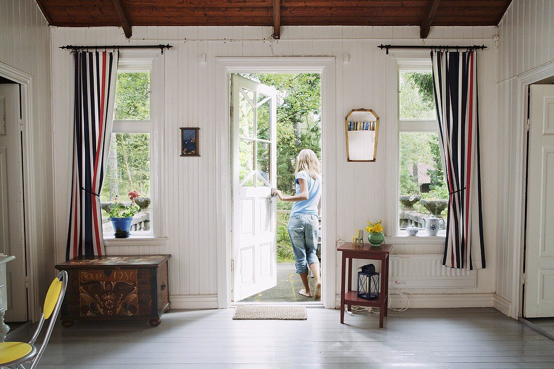 A wood panelled front room in a country house and a girl at a garden door