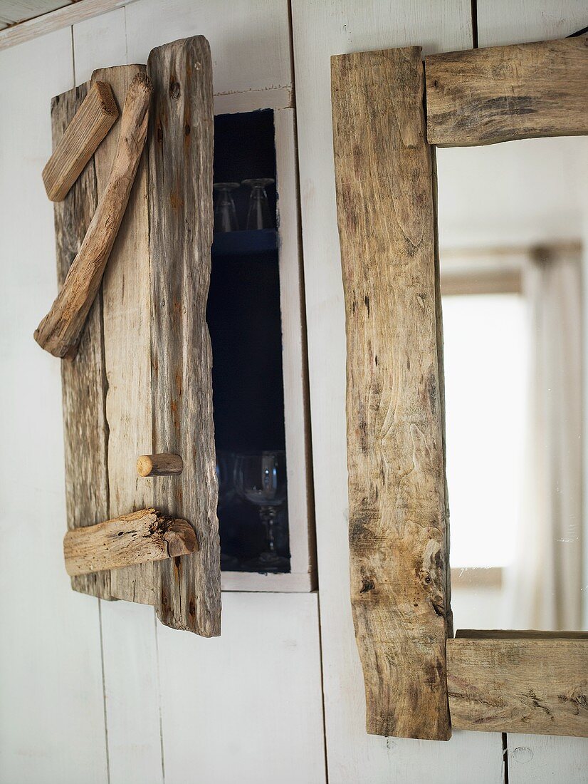 A homemade wooden door for a built-in cupboard and a mirror on a wall