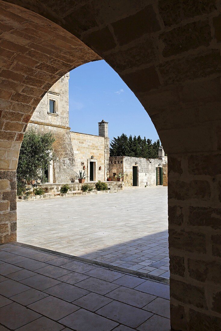 View through an archway of a stone piazza and historic buildings