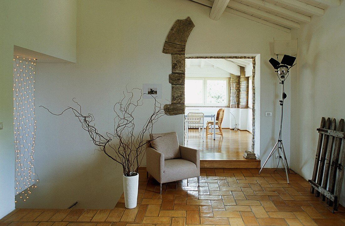 Eingangsbereich eines südländischen Landhauses mit Sessel auf Fliesenboden und Blick in Wohnraum