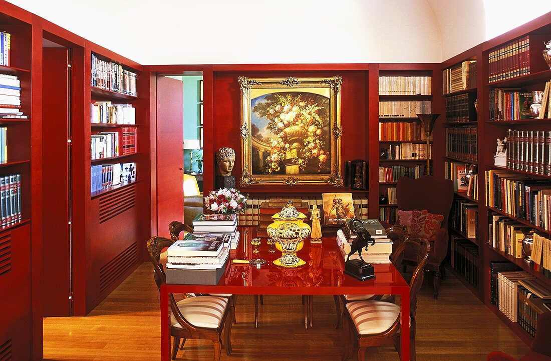 Rotlackierter Tisch in Bibliothek mit rotverkleideten Wänden und eingebauten Bücherregalen