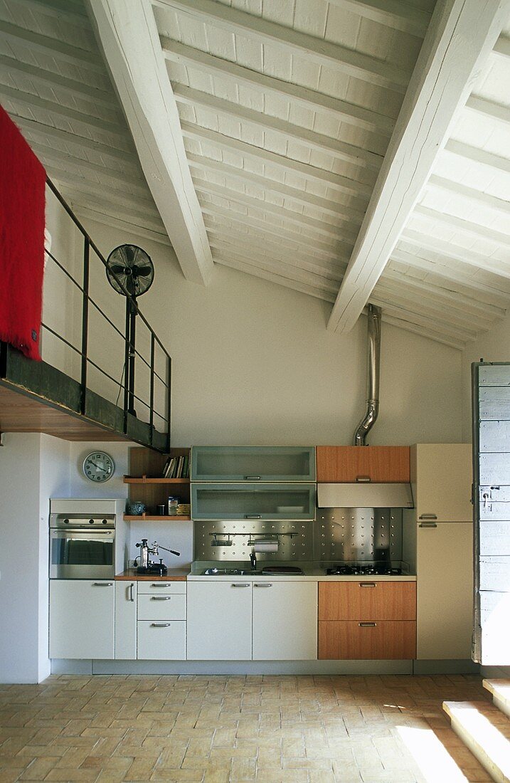 Offene Küche im Wohnraum eines Landhauses mit Blick auf weiße Holzdecke und Galerie
