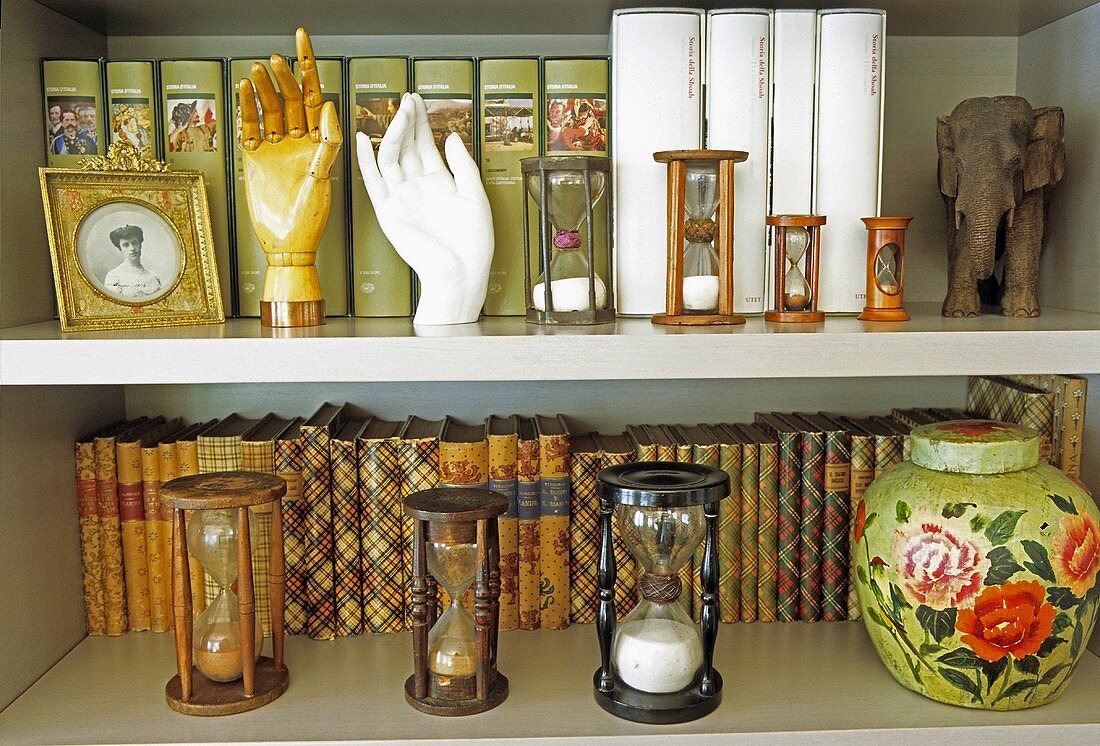 Close up of shelving with antique volumes and an antique collection of hourglasses