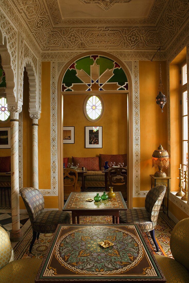 Eleganter marokkanischer Salon mit Wandbemalung und Blick durch Rundbogen auf Sofa