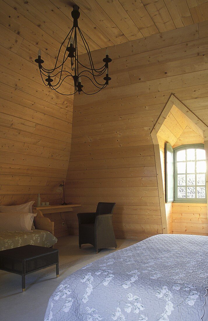 Schlafzimmer im Dachraum mit heller Holzvertäfelung an Wand und Decke